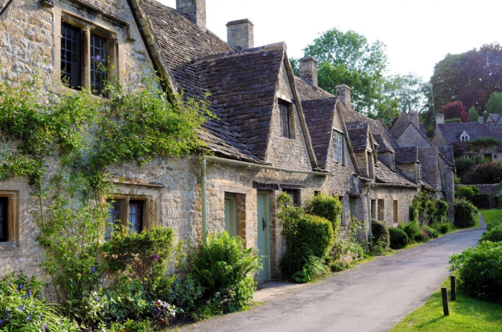 stone cottages with ivy walls stand along a serene village path, bathed in soft sunlight